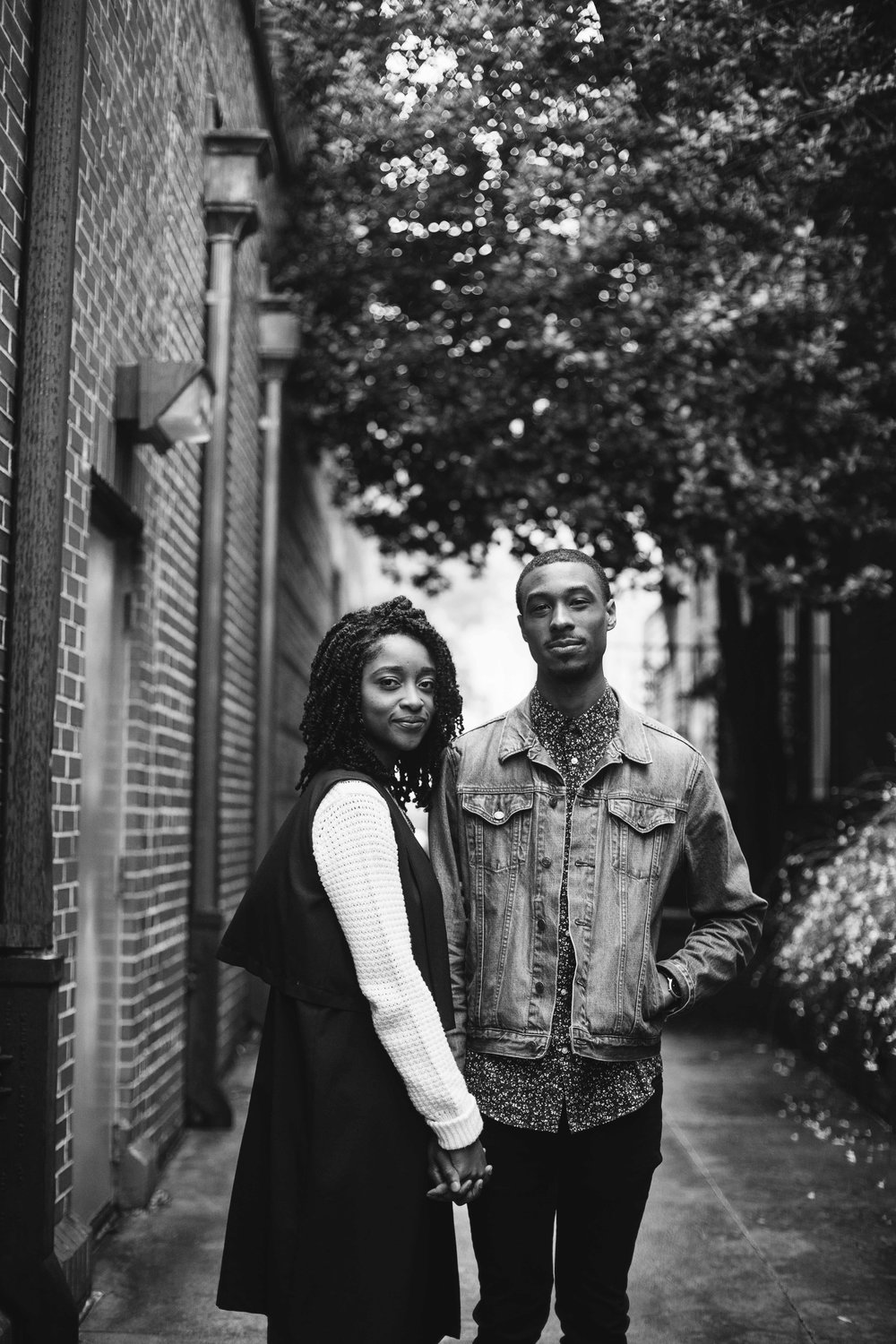 black and white engagement photo next to brick building 