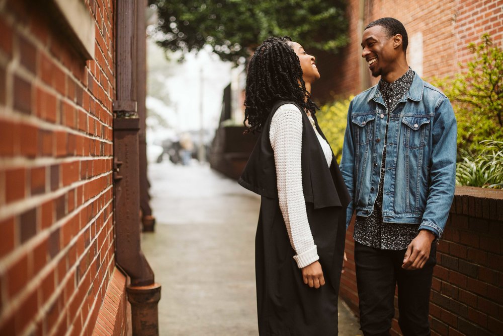  engagement photos of couple by brick wall 