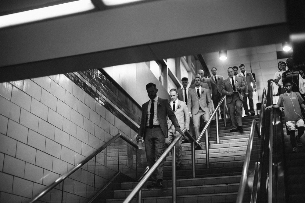  The groom and groomsman walking to the wedding in their gray suits in the Subway at this Battello Wedding in Jersey City, NJ 