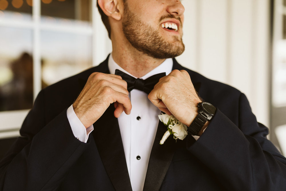  groom putting on bow tie 