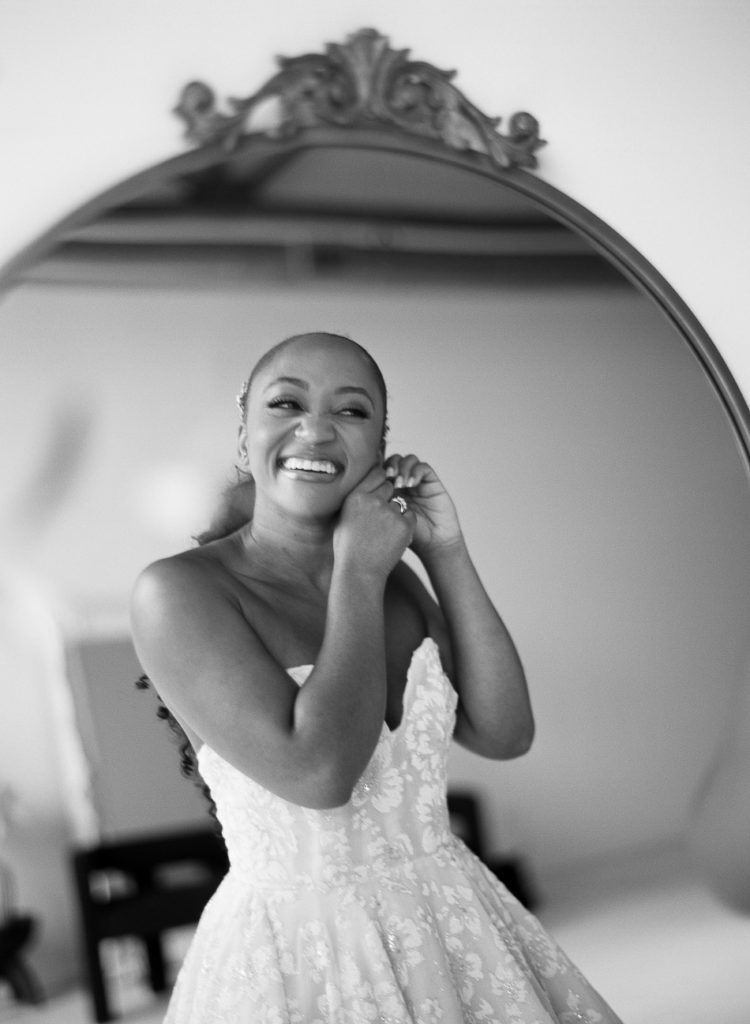 smiling bride puts on earrings at winter wedding at summerour
